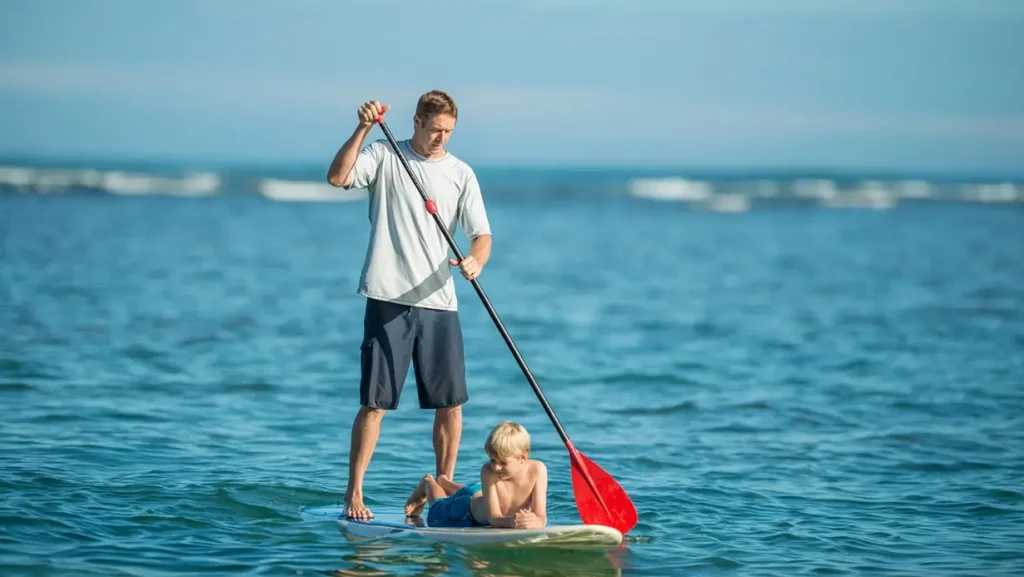 a man paddleboarding with his son